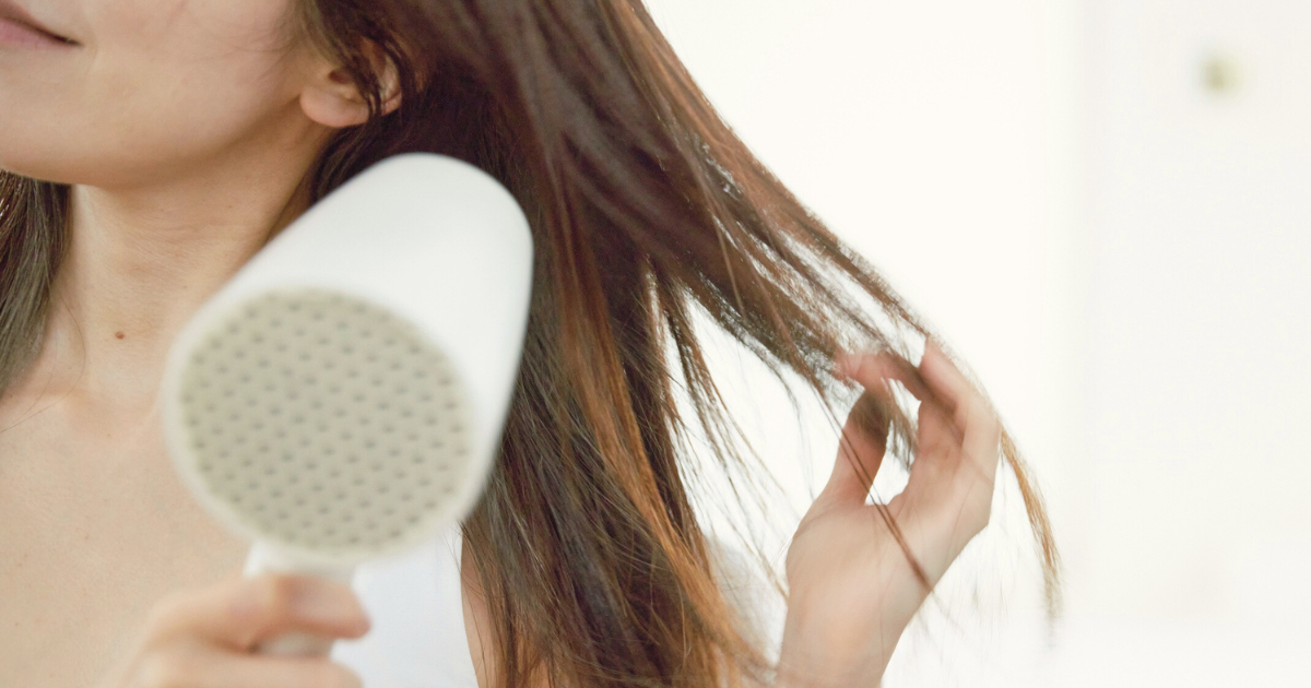 ドライヤーを根元から毛先に向けて正しく風を当てて髪を乾かしている様子